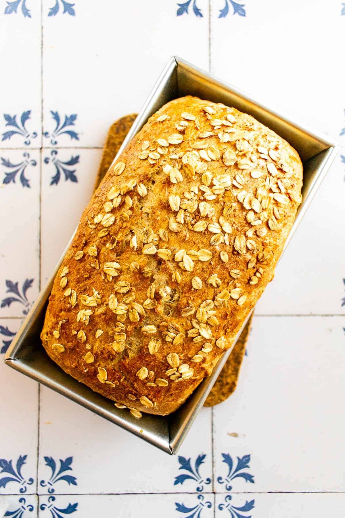 A loaf of golden baked bread topped with oats and honey.