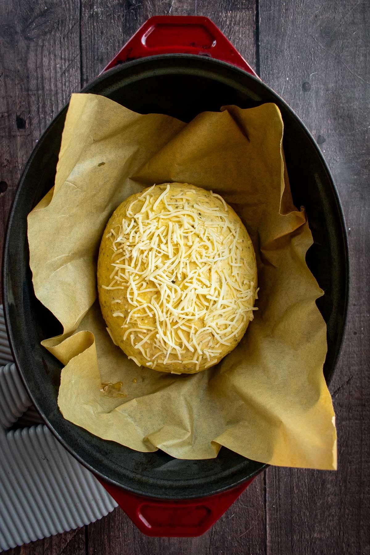 An unbaked bread loaf with Italian cheese in a Dutch oven.
