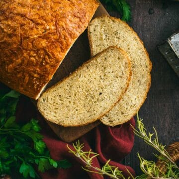 Two slices of bread on a board next to the rest of the artisan loaf.