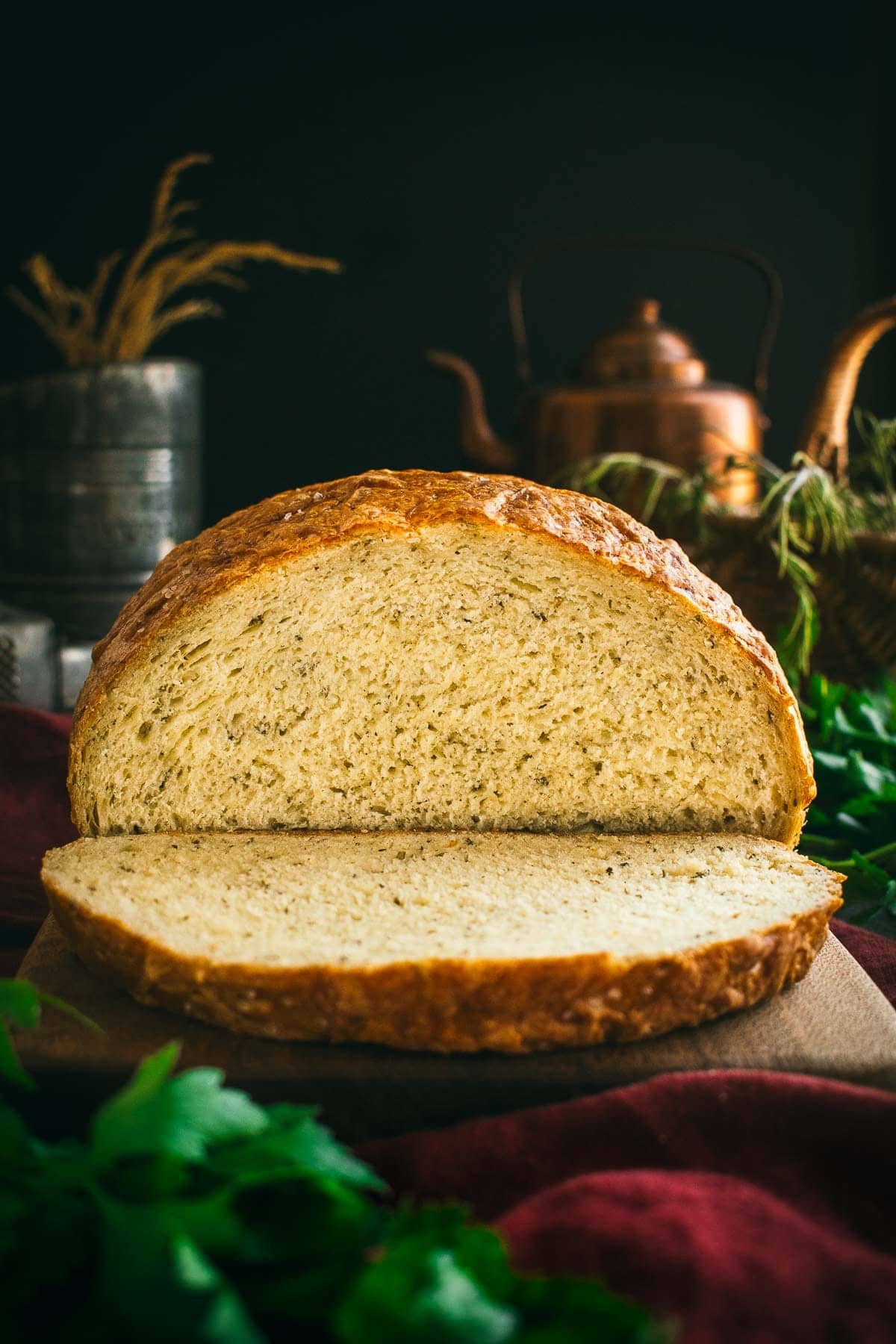 A sliced loaf of Italian herb cheese bread on a cutting board.
