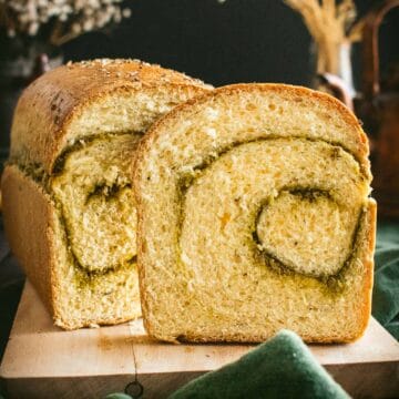 A sliced loaf of bread with a swirl of pesto inside.