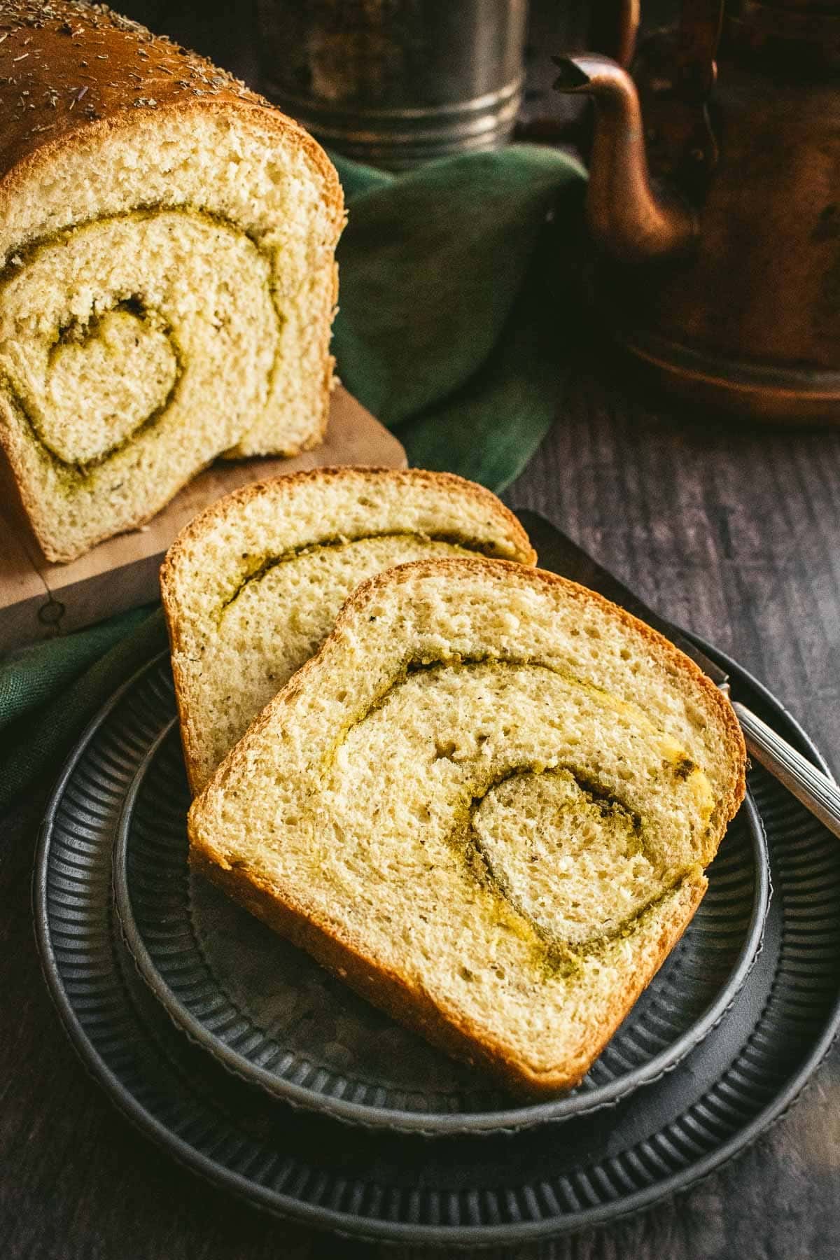 Two slices of pesto bread on a metal plate.