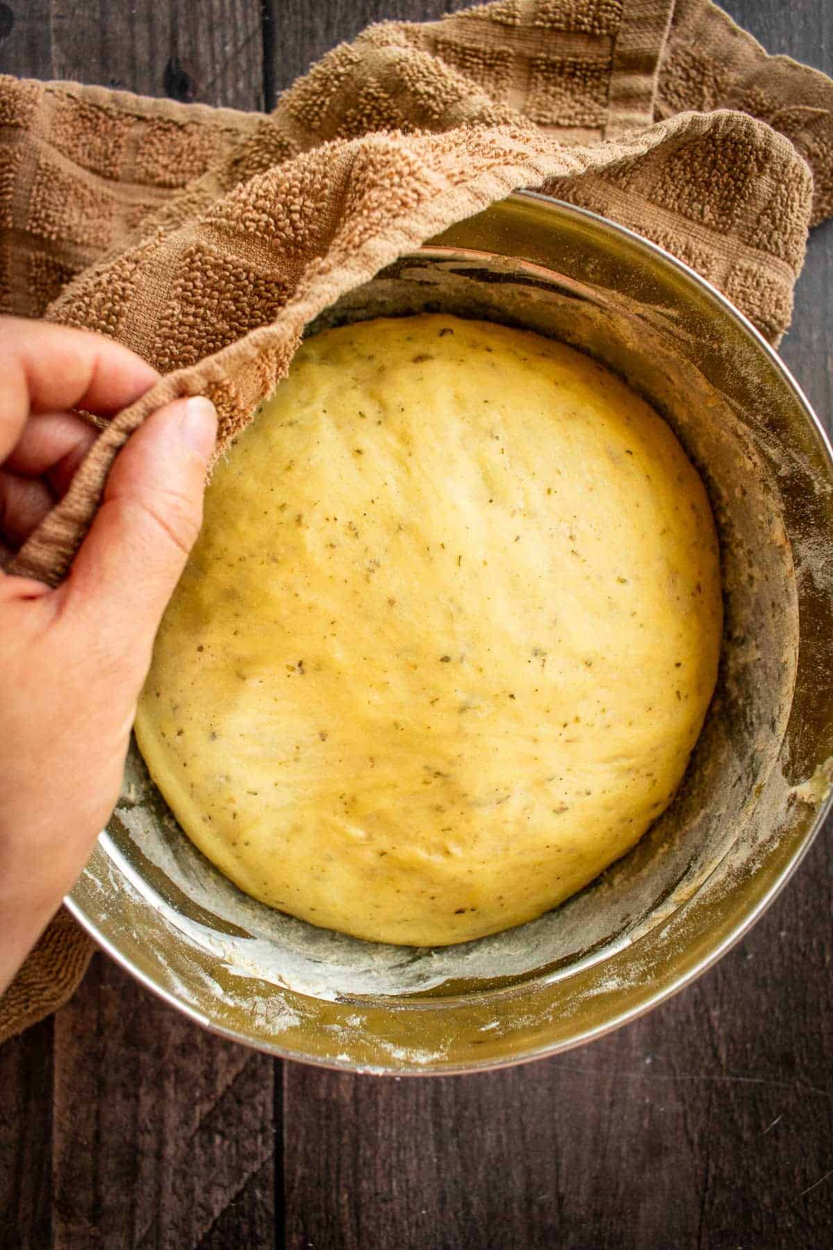 Risen bread dough in a metal mixing bowl.