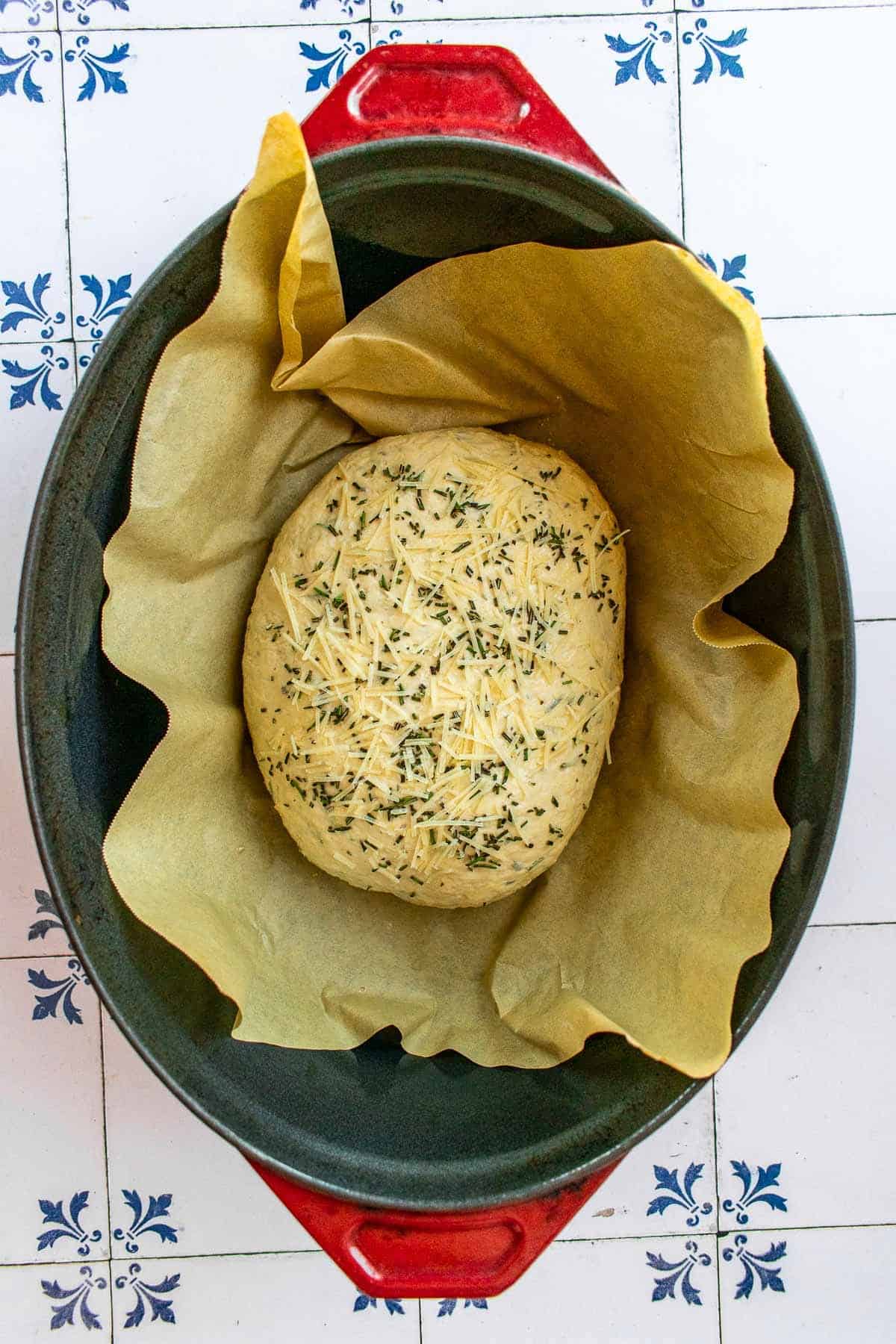 A loaf of unbaked rosemary bread in a Dutch oven.