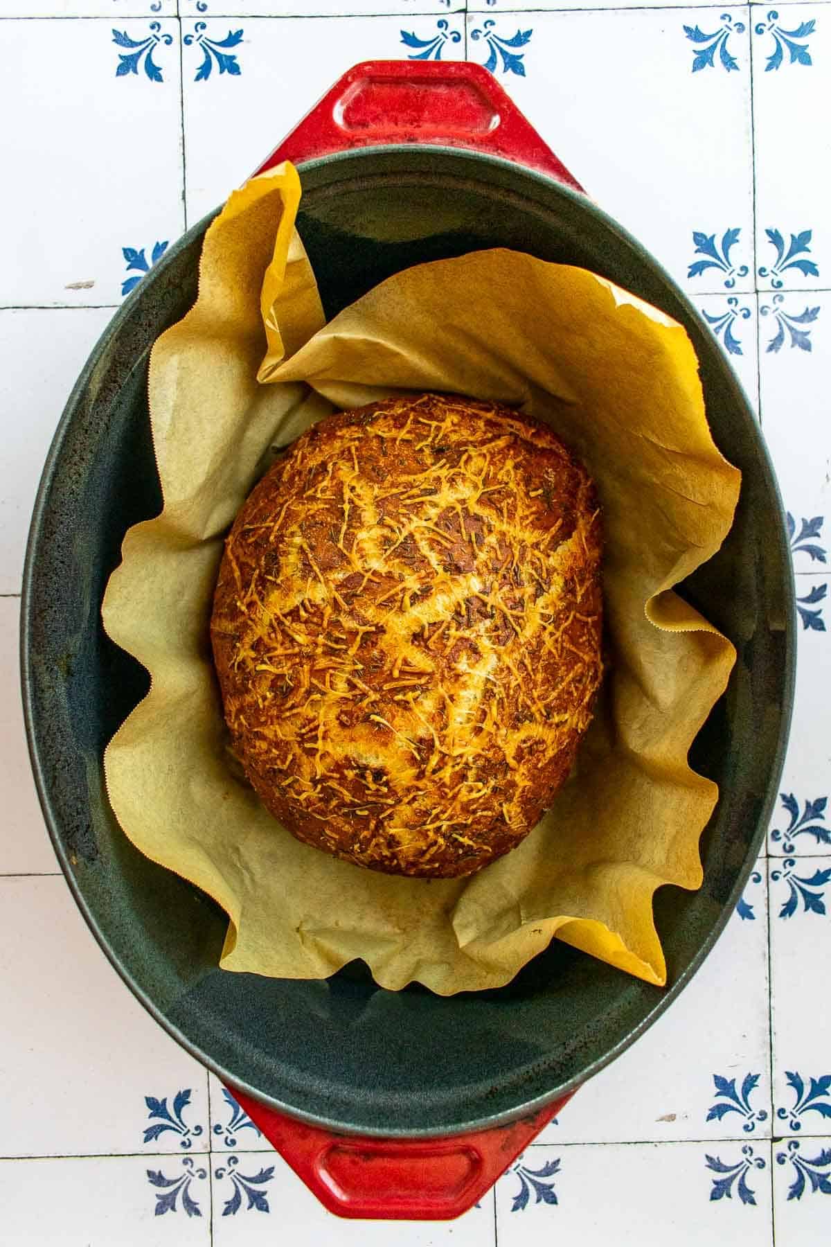 A loaf of baked rosemary bread in a Dutch oven.