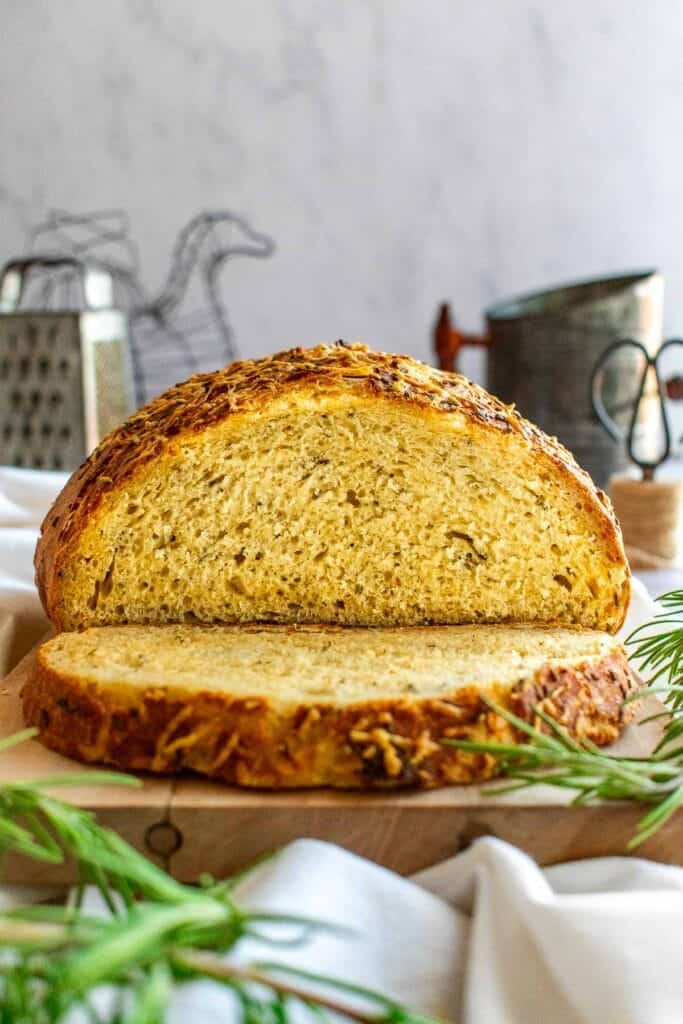 A sliced loaf of rosemary butter on a cutting board.