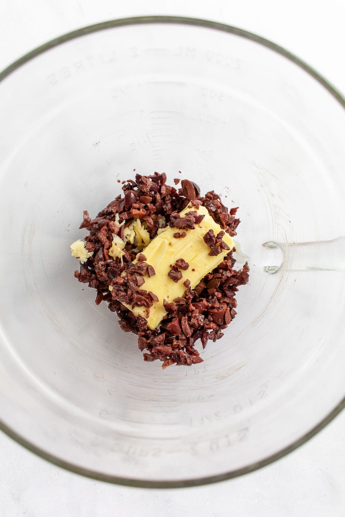 Chopped olives and a stick of butter in a bowl. 