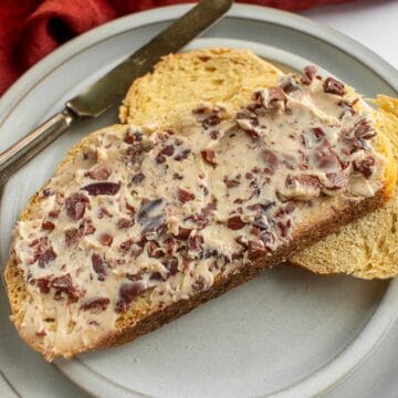 Two slices of bread on a plate, with one covered in olive butter.