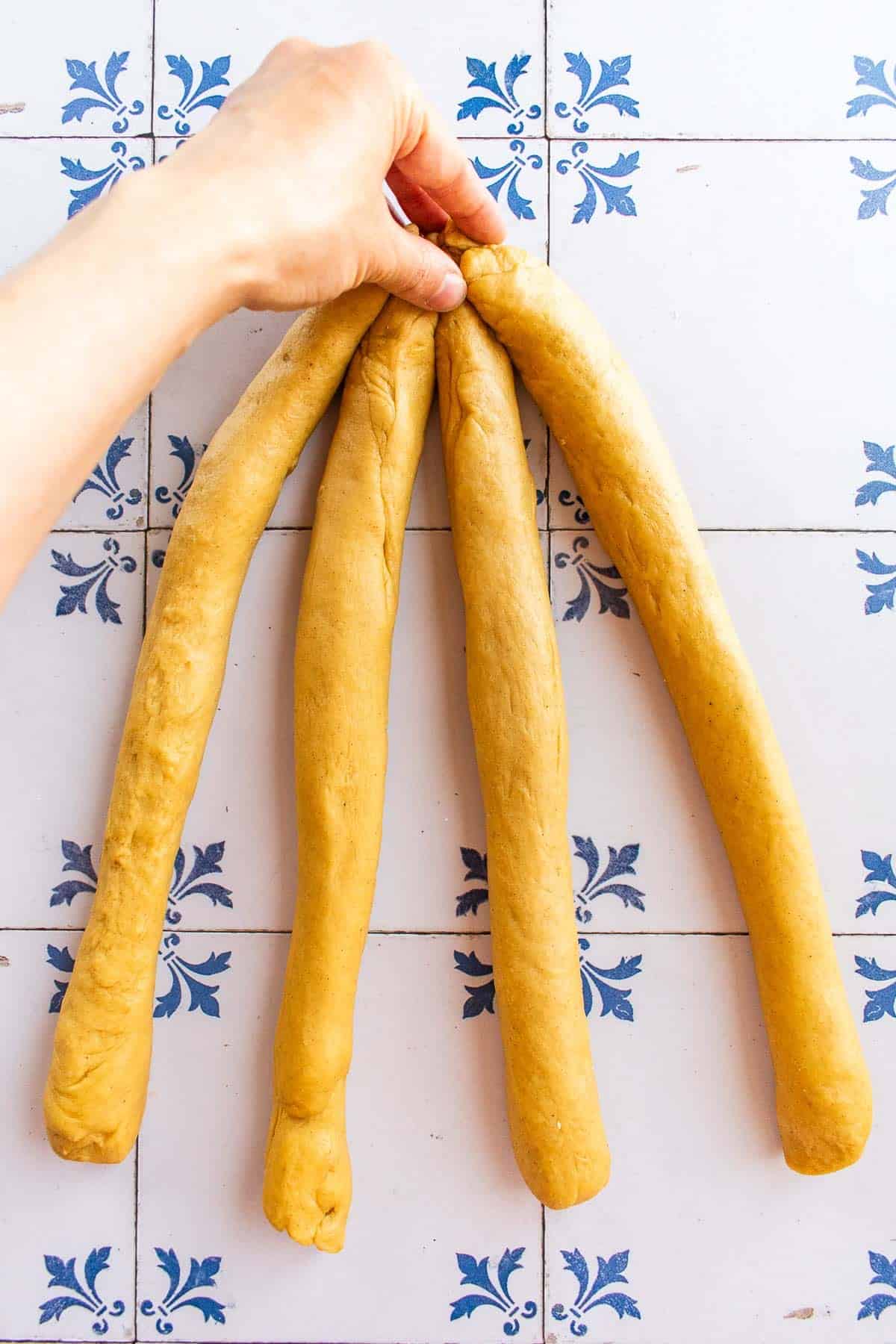 Four strands of dough pinched together at the top.