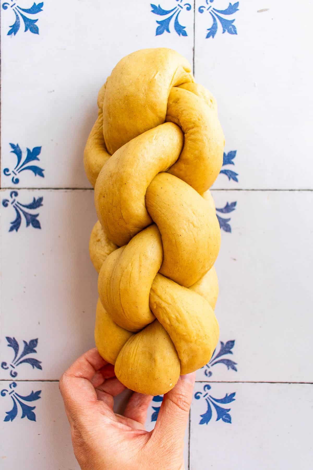 An unbaked four-stranded braided loaf on a table.