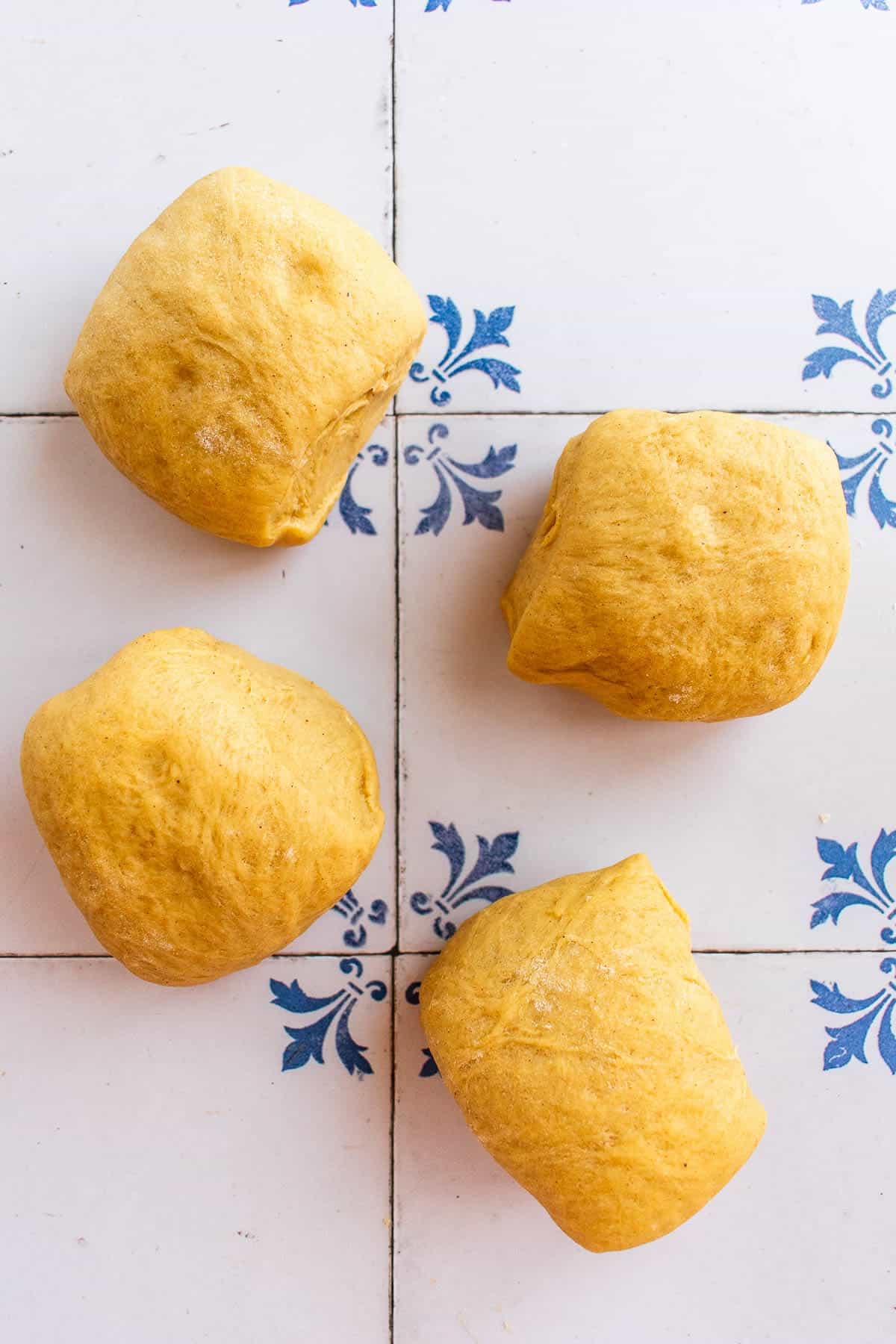 Four balls of bread dough on a table.