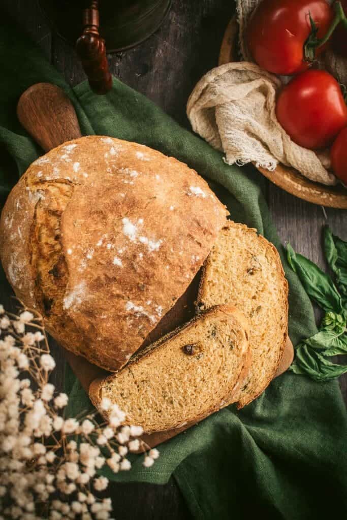 Two slices of tomato basil bread next to the rest of the loaf.