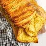 Two slices of pull apart cheese bread next to the rest of the loaf.