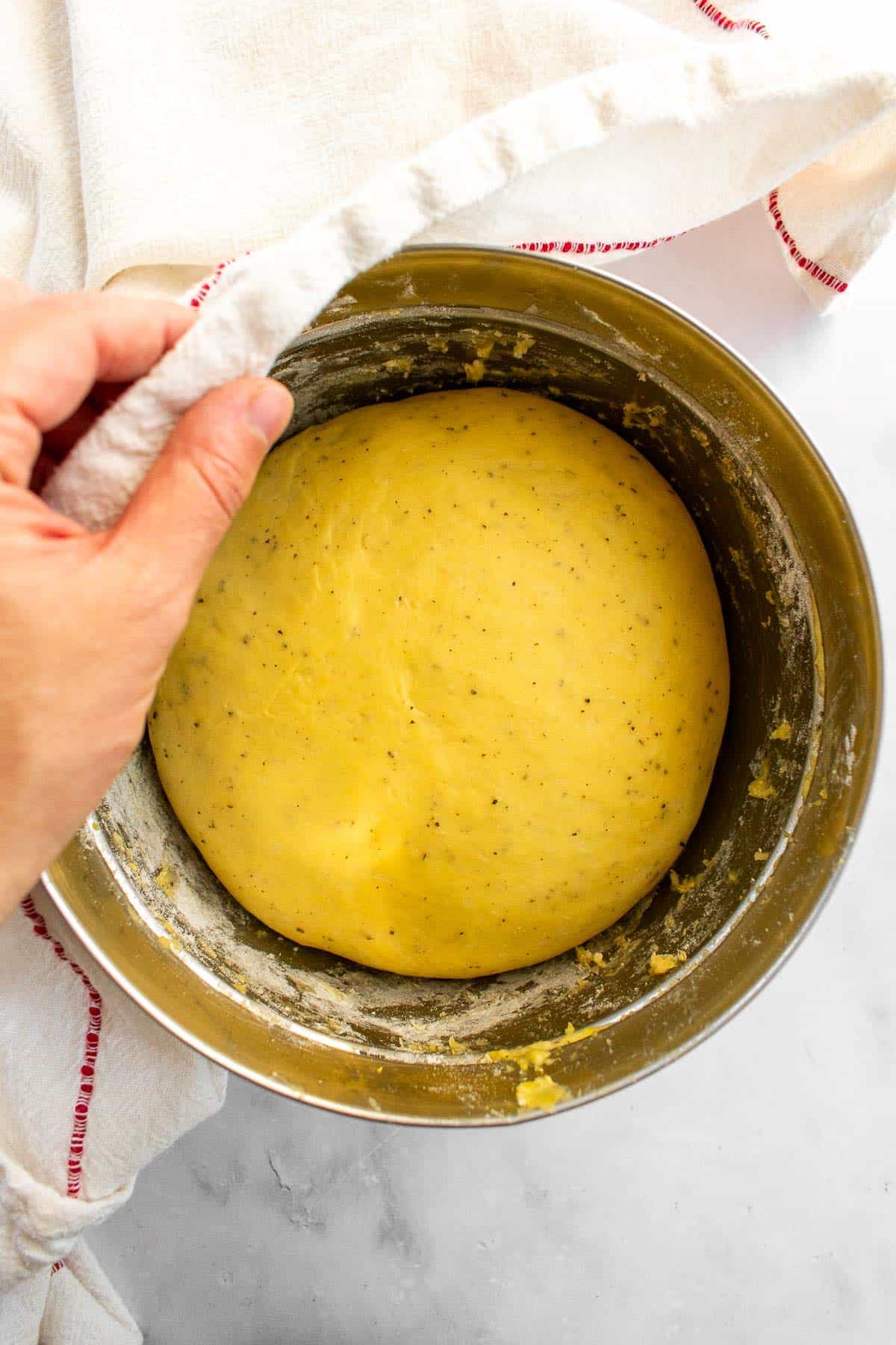 A large ball of proofed enriched bread dough in a metal bowl.