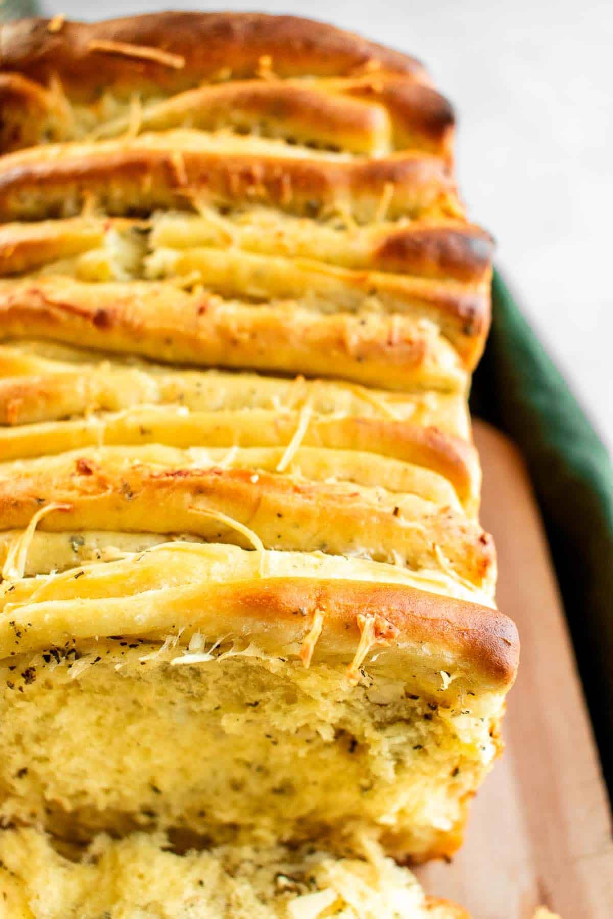 A loaf of garlic pull apart bread on a wood cutting board.