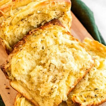 Slices of garlic bread on a wooden board.