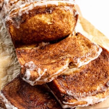 A loaf of cinnamon and brown sugar bread with slices on a cutting board.
