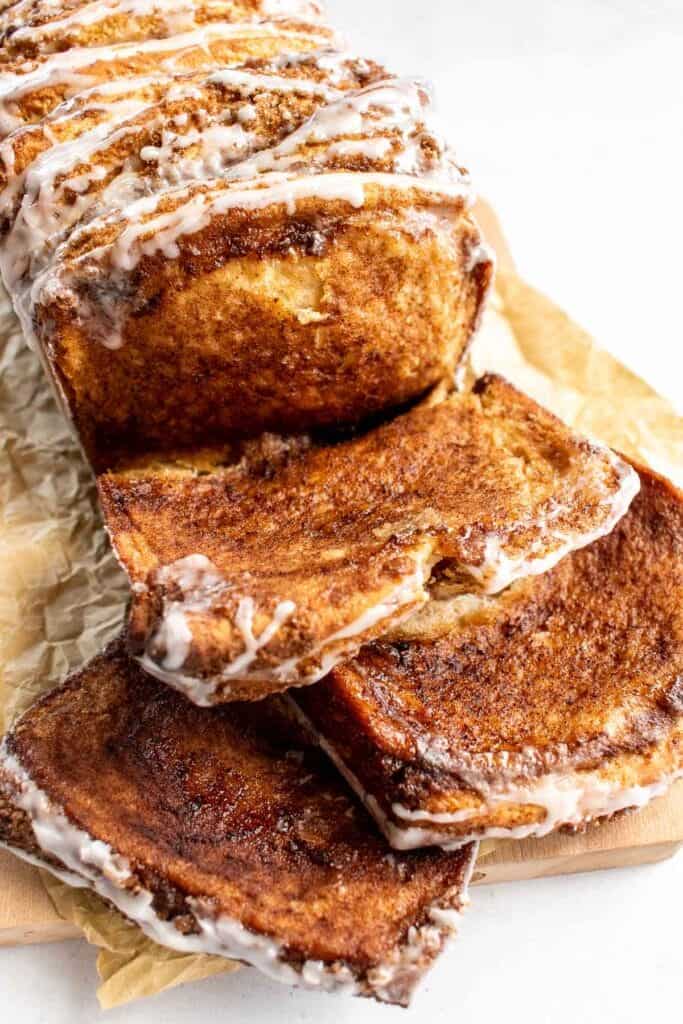 A loaf of cinnamon and brown sugar bread with slices on a cutting board.