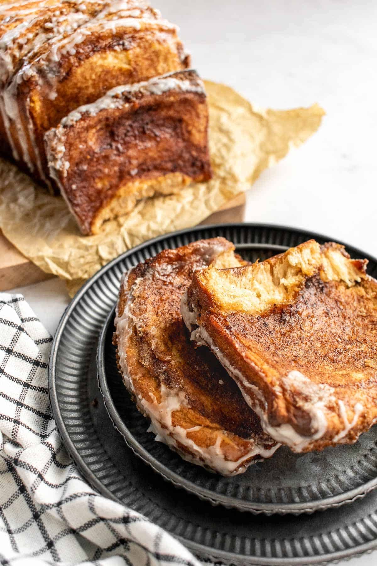 Two slices of glazed cinnamon bread on a metal plate.