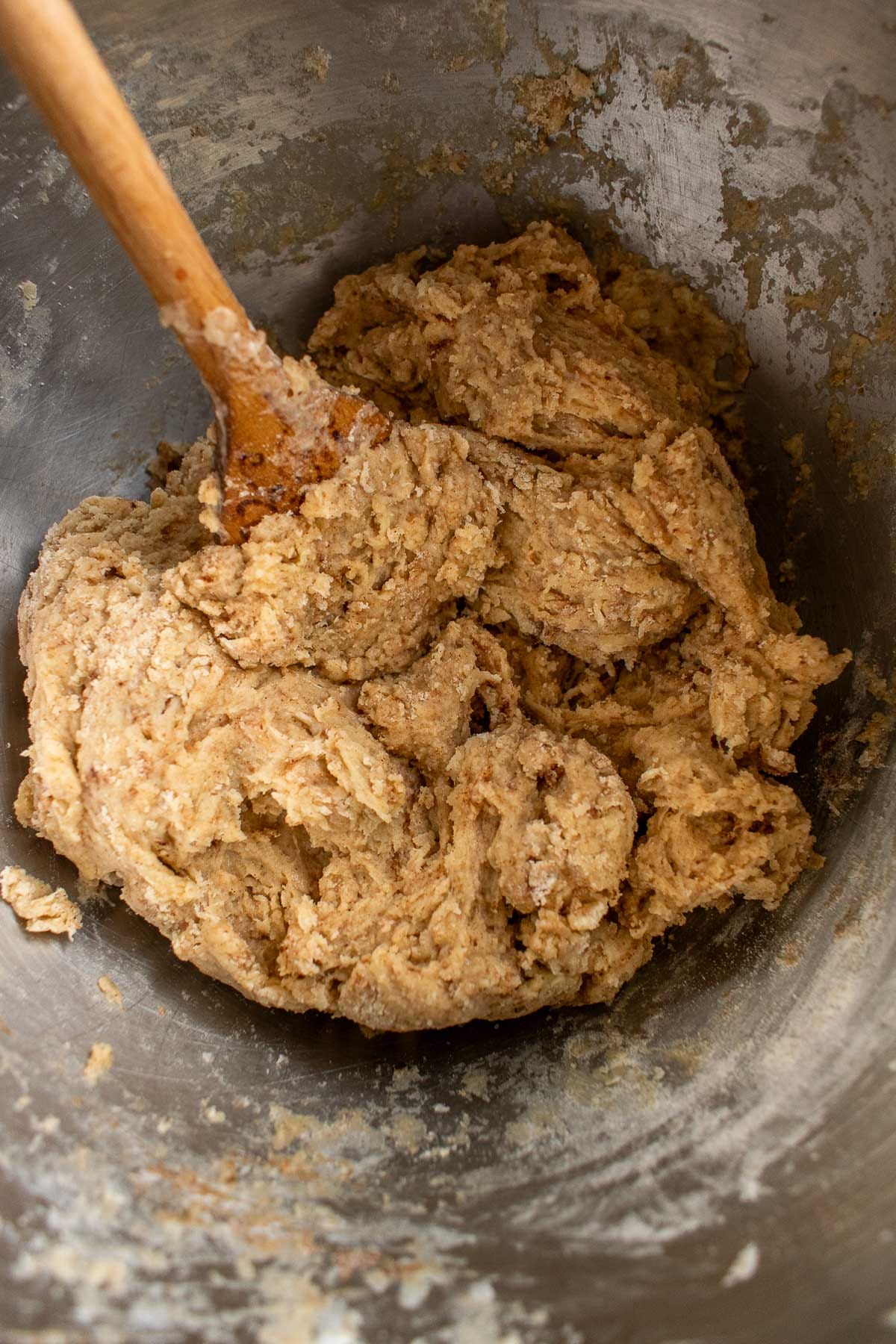 A light brown bread dough in a bowl with a wooden spoon.