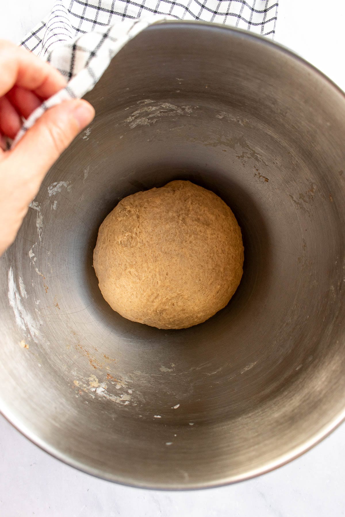 A ball of kneaded bread dough in a metal bowl.