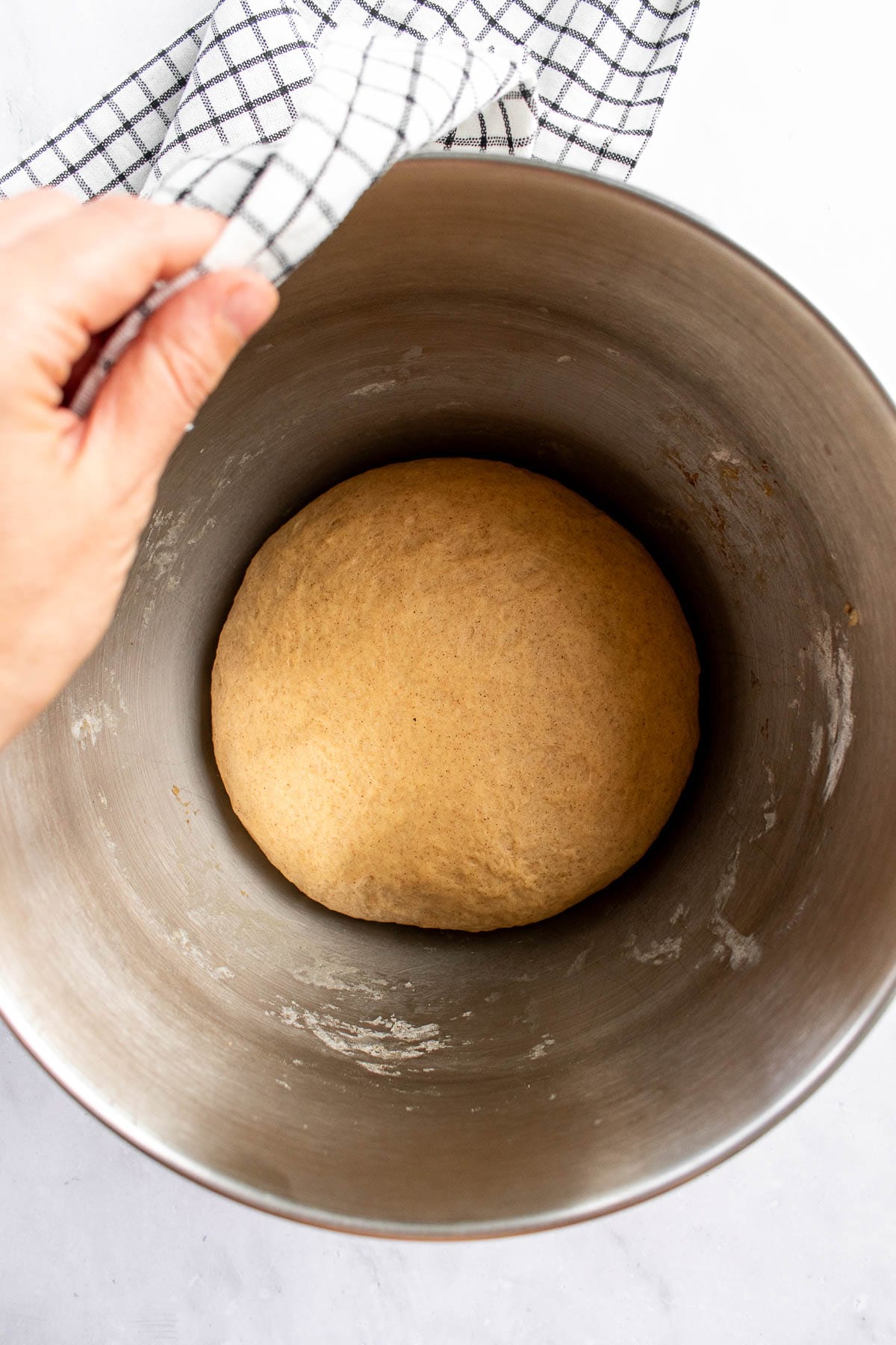 A ball of risen light brown bread dough in a bowl.