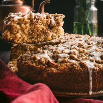 A slice of glazed coffee cake being lifted up by a metal cake server.