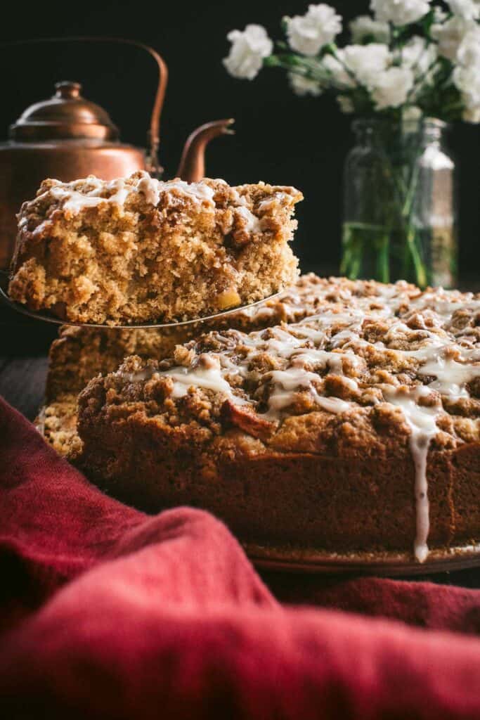 A slice of glazed coffee cake being lifted up by a metal cake server.