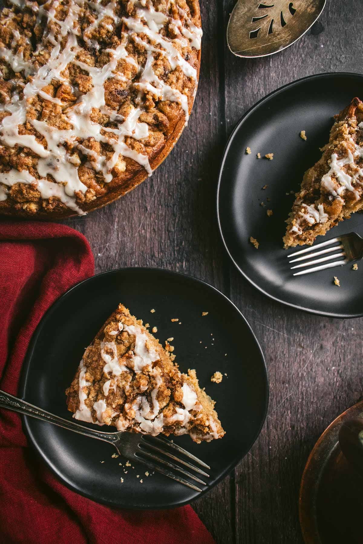 Two slices of glazed coffee cake on black plates.