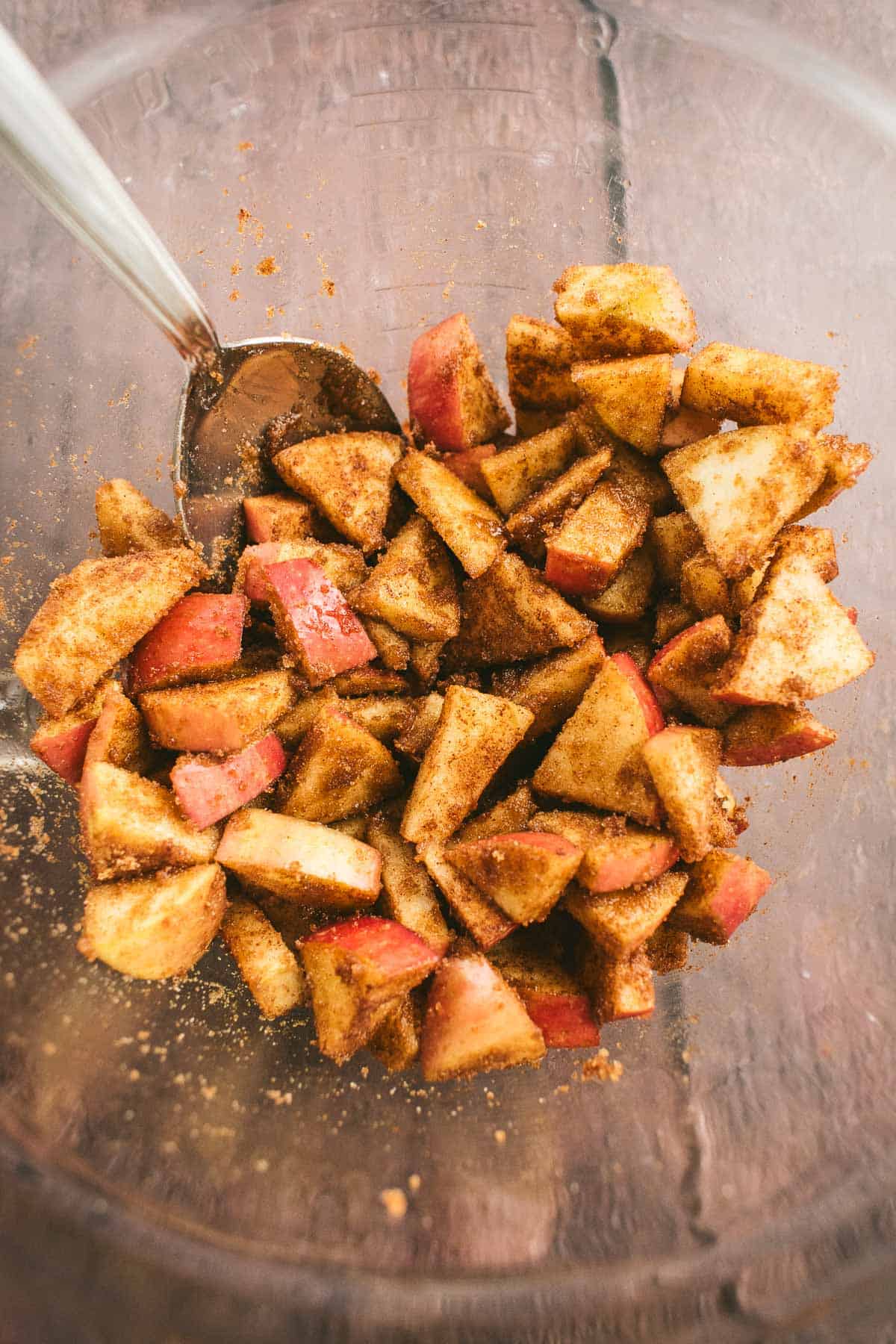 Chopped apples in a bowl covered in cinnamon and brown sugar.