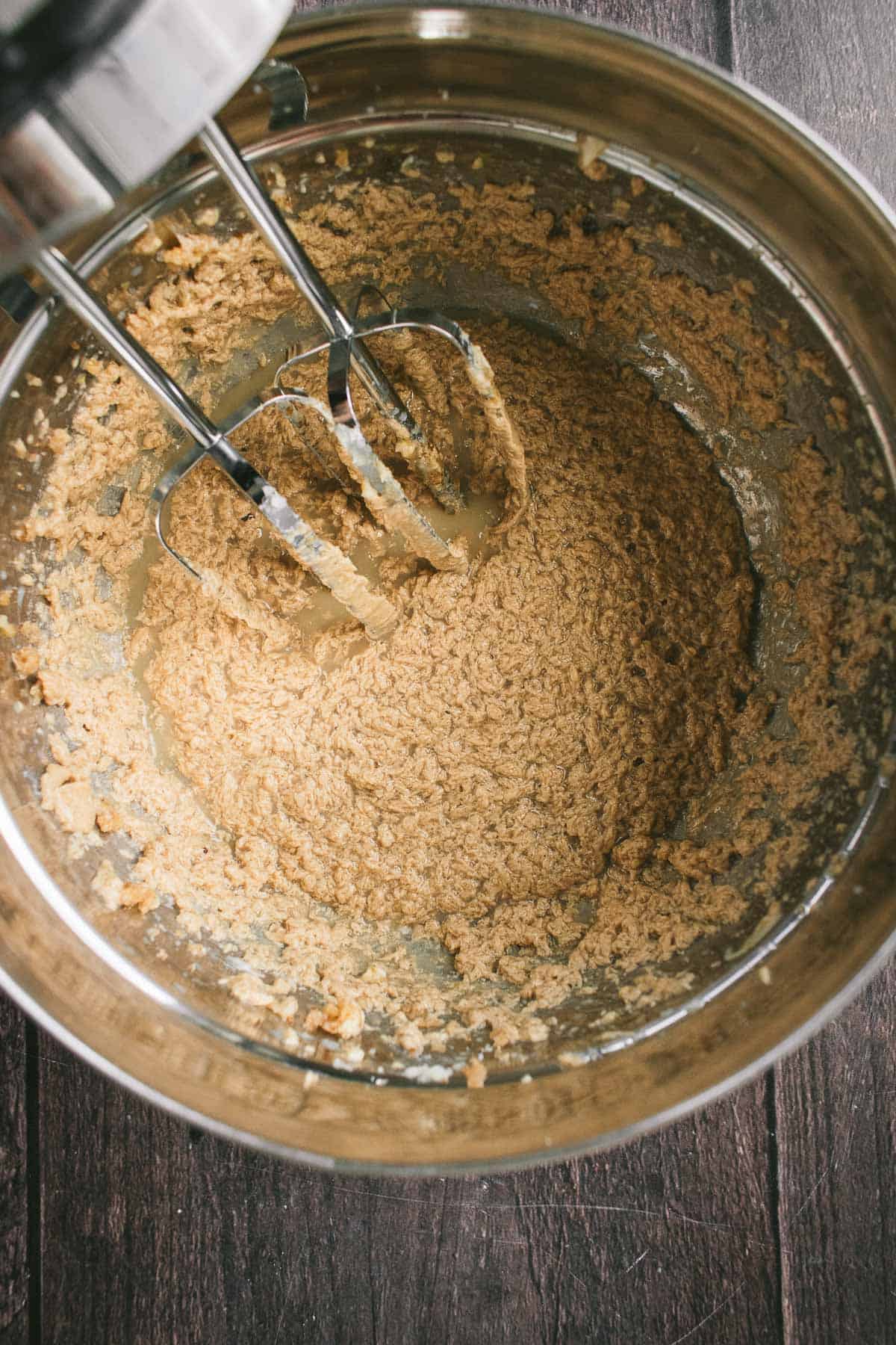 Milk, butter, sugar, and eggs mixed in a bowl with metal beaters.