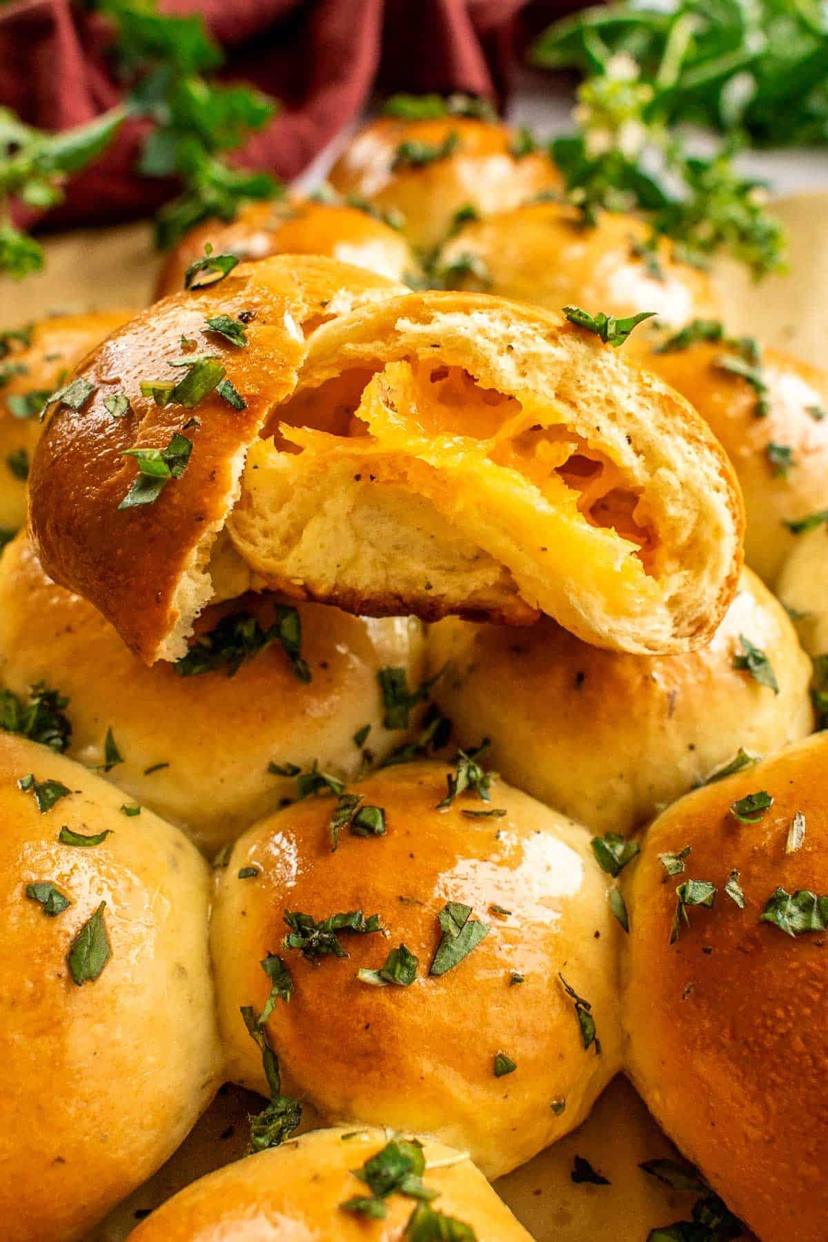 A cheese-filled bread bun torn in half and topped with chopped herbs. 