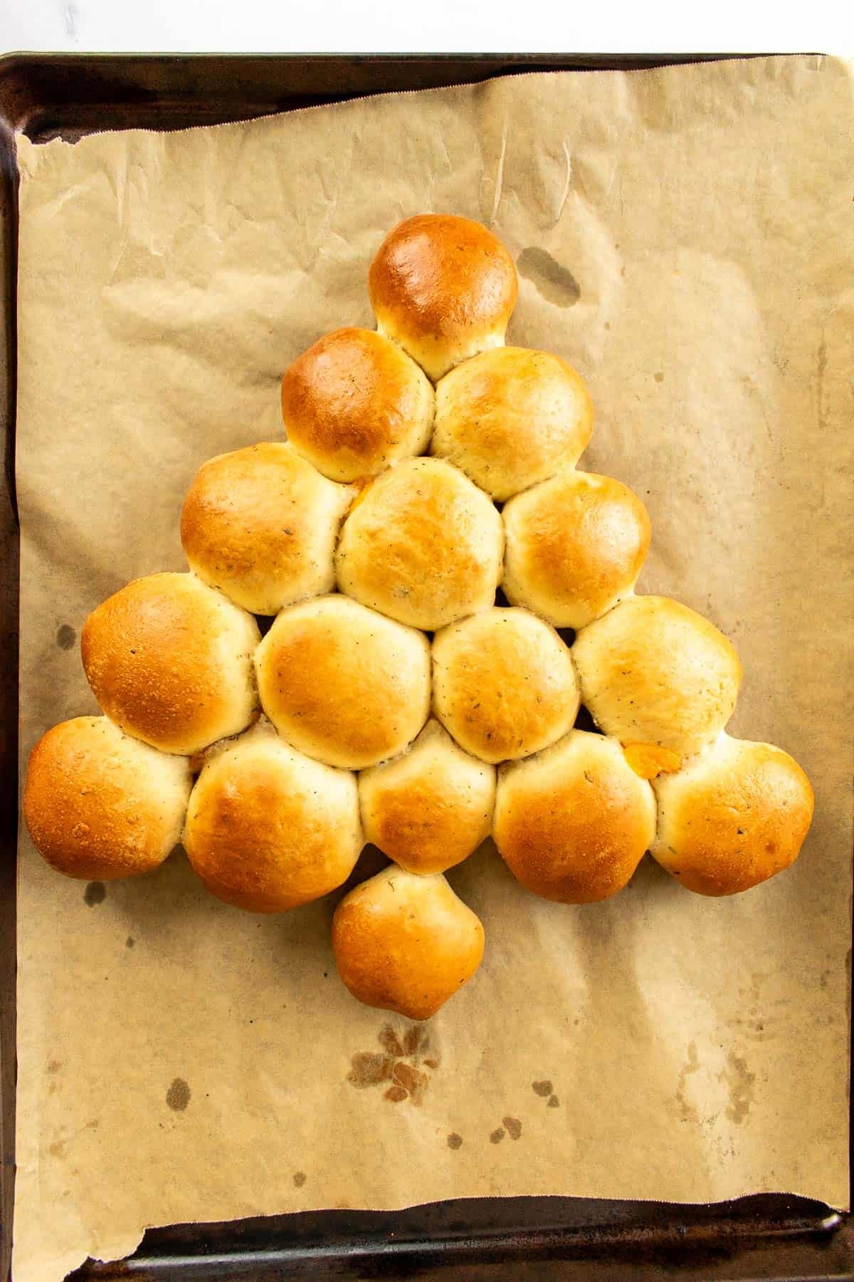 Baked bread rolls on a baking sheet arranged in the form of a Christmas tree. 