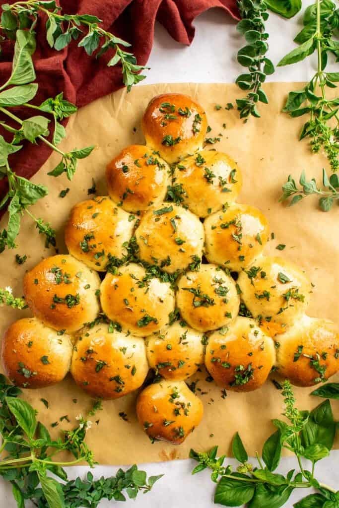 Bread buns topped with chopped herbs and arranged in the shape of a Christmas tree.