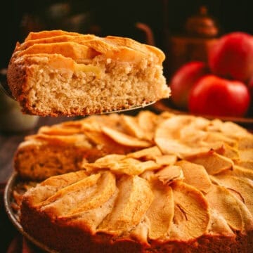 A slice of apple cake on a metal server being lifted from the rest of the cake.