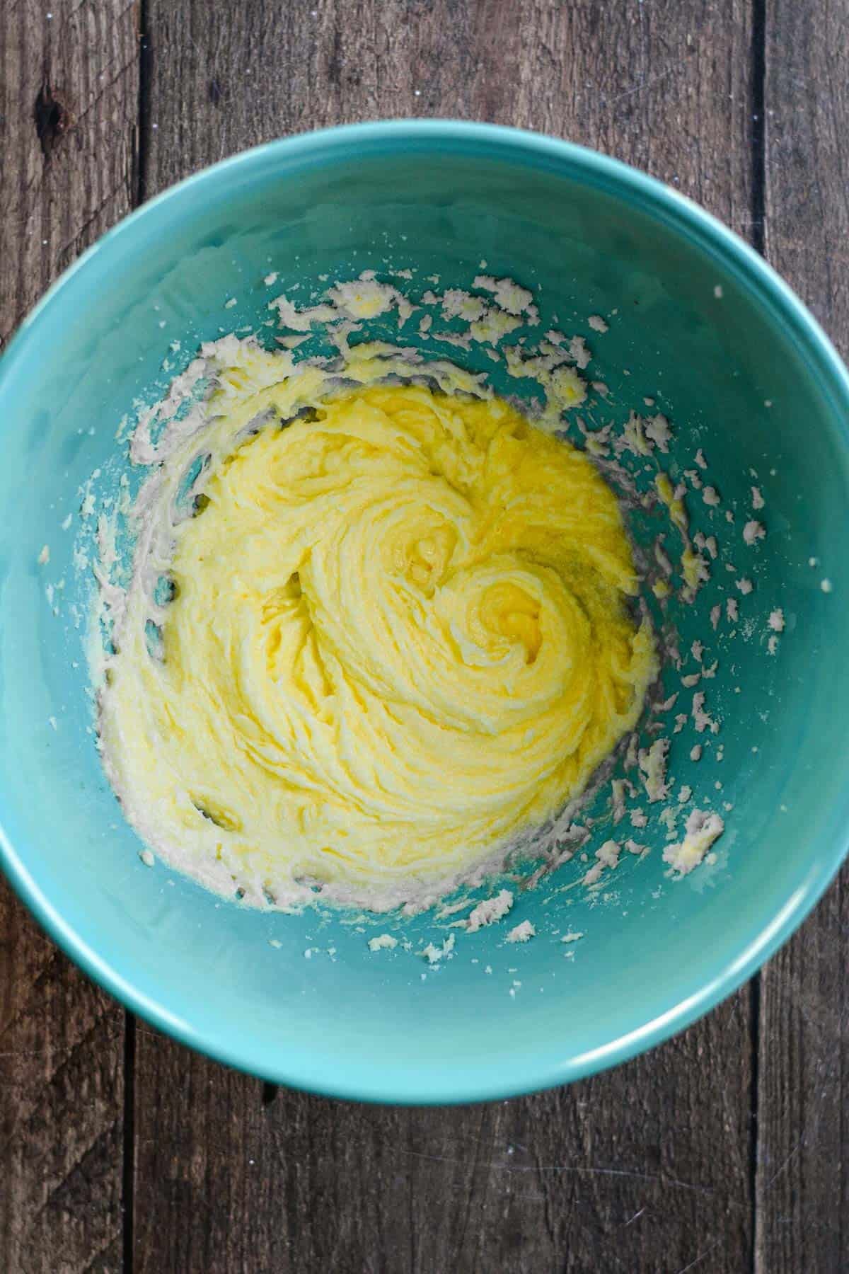 Butter, sugar, and eggs beaten in a blue bowl.