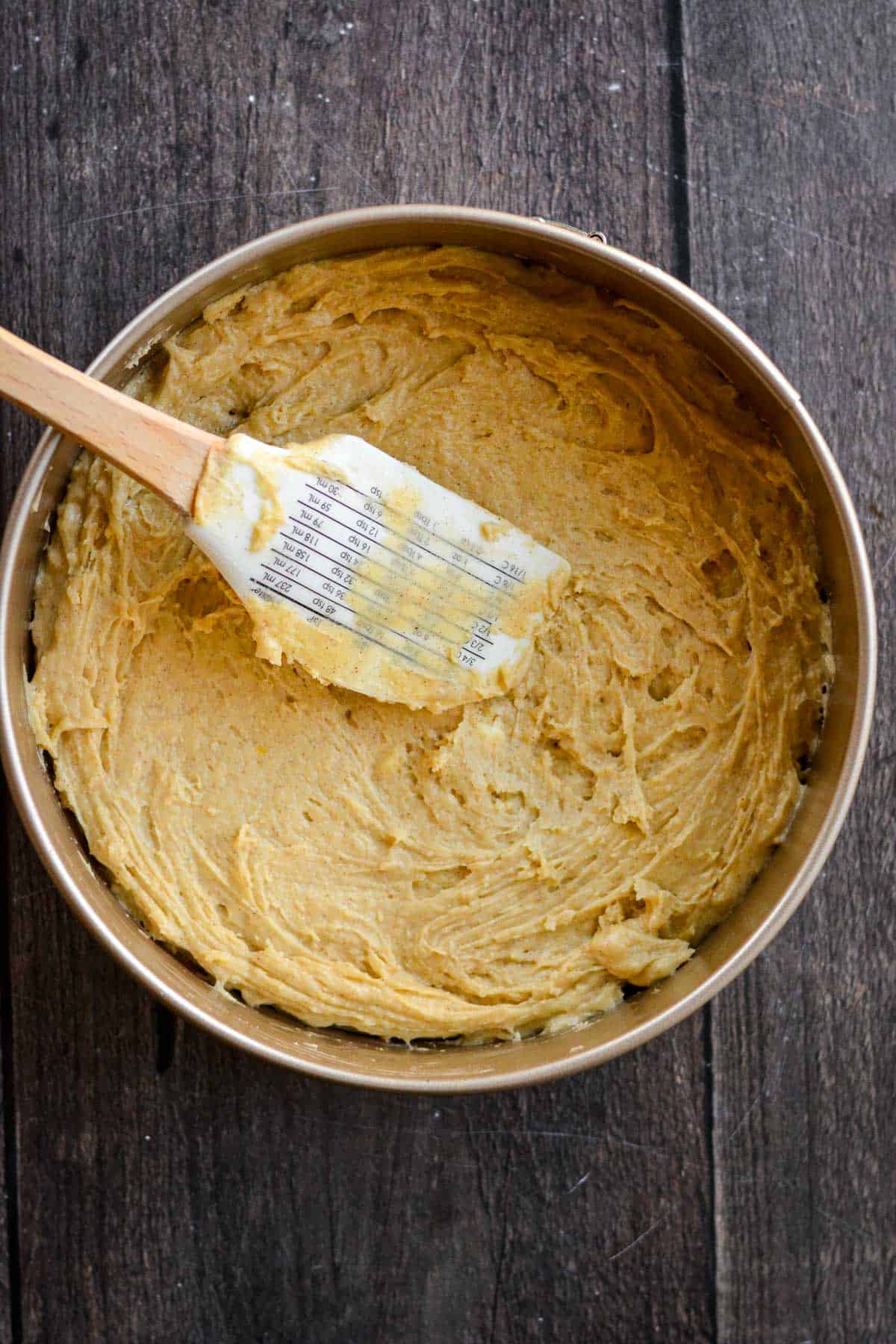 Cake batter spread in a cake pan with a spatula.