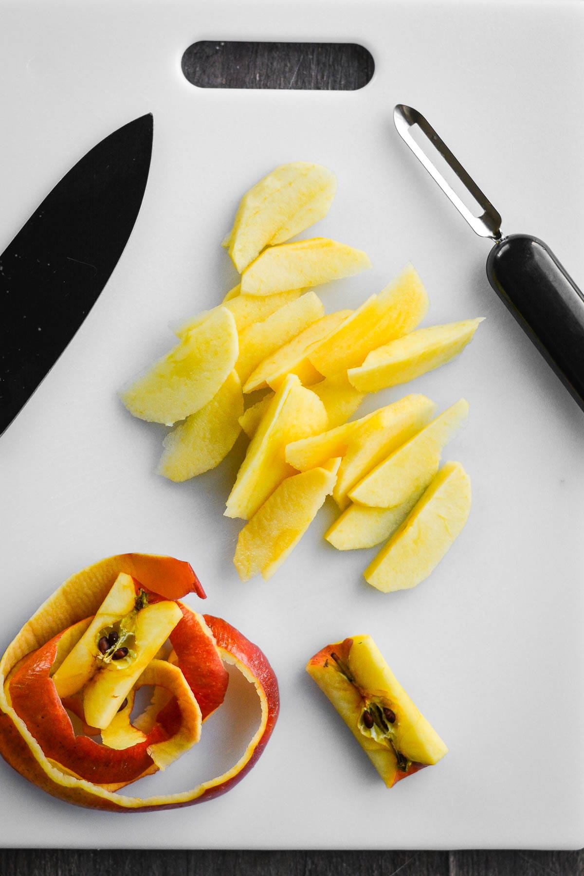 A peeled and sliced apple on a cutting board.