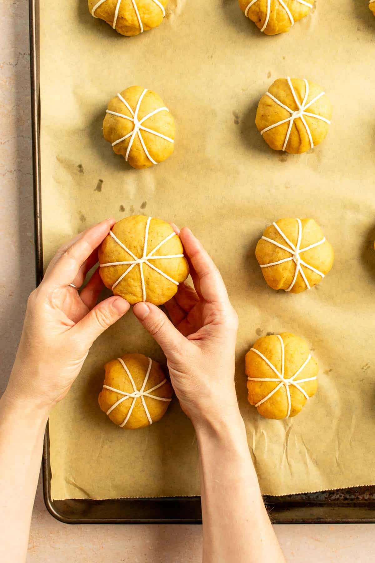A dozen balls of bread dough wrapped in baking string on a baking sheet.