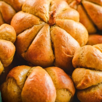 Pumpkin shaped bread rolls in a basket on a green linen.