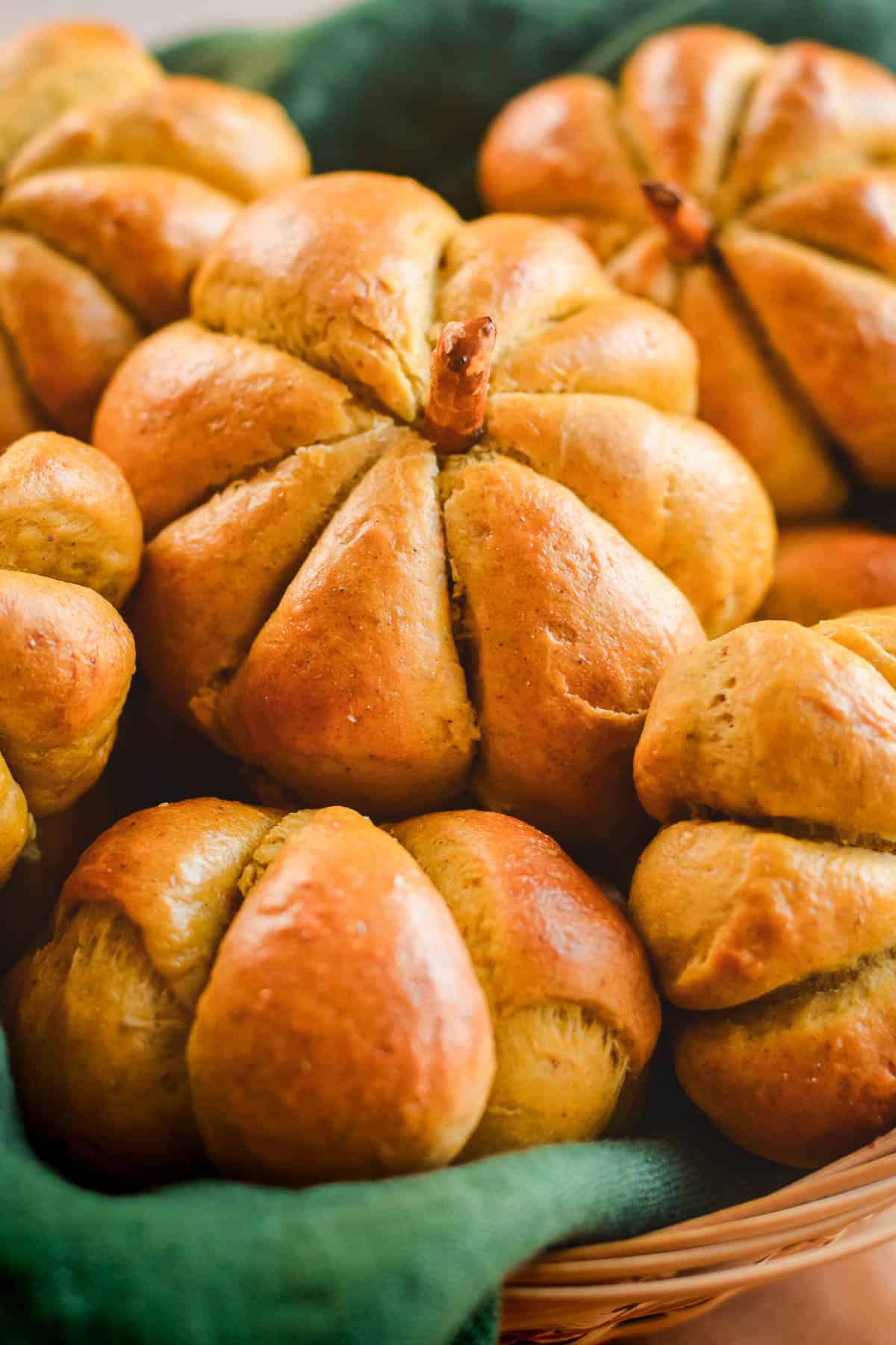 Pumpkin shaped bread rolls in a basket on a green linen.