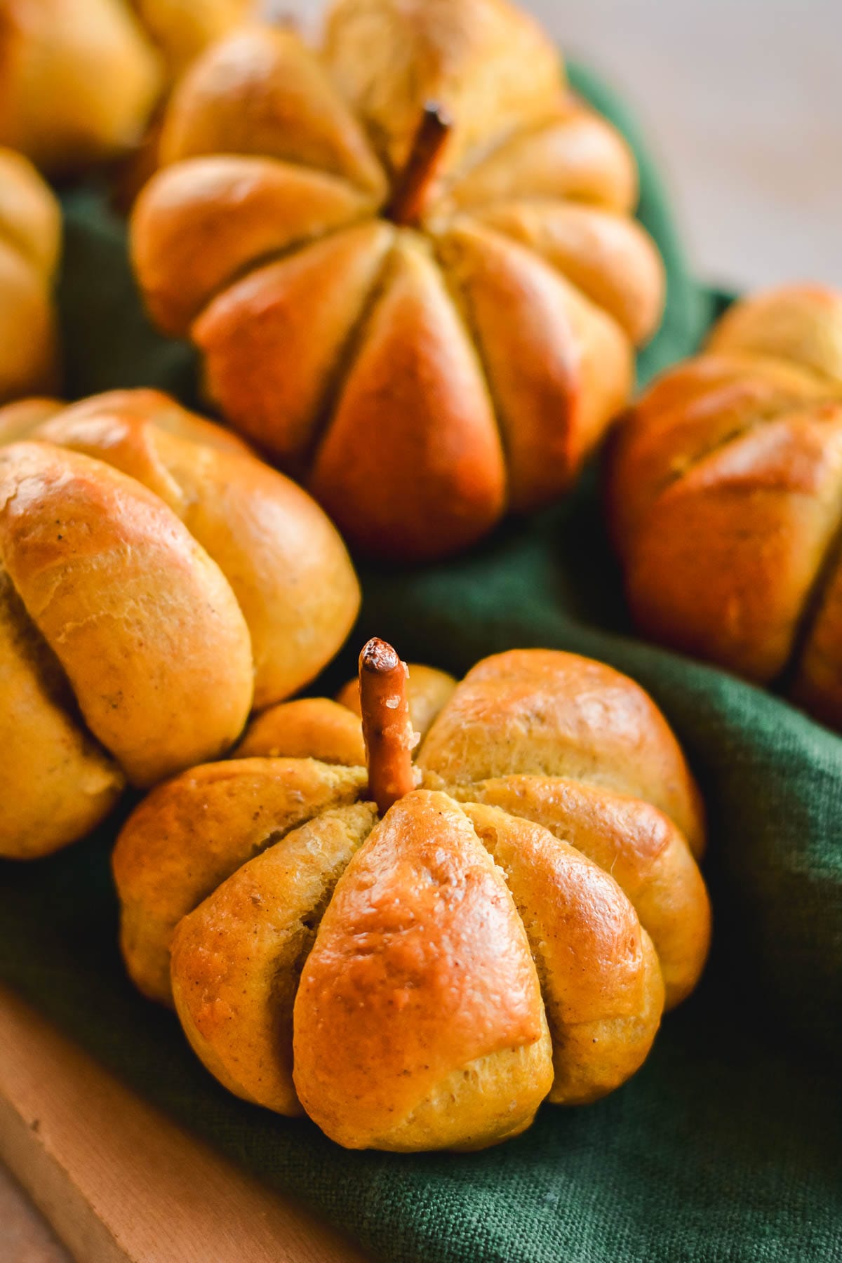 Pumpkin shaped buns piled on a green linen.