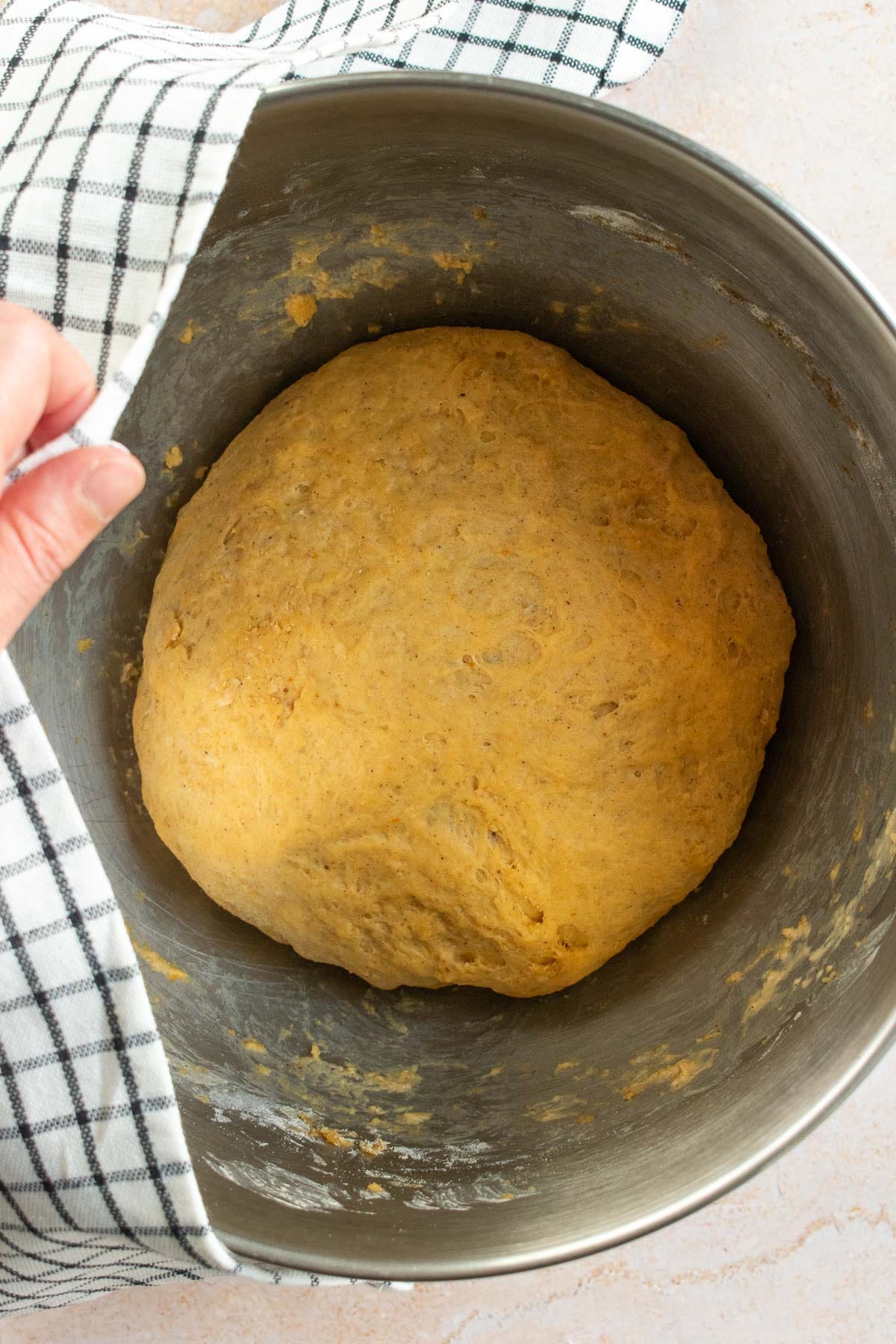 A large ball of risen bread dough in a metal bowl.
