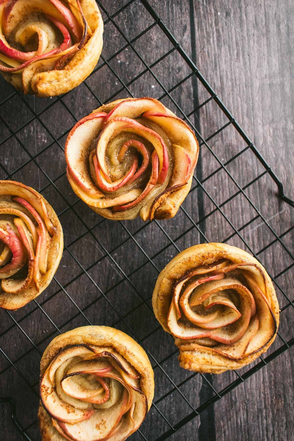 Baked apple rose puff pastries on a wire cooling rack.