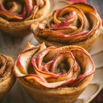 Puff pastry cups filled with sliced apples on a plate.