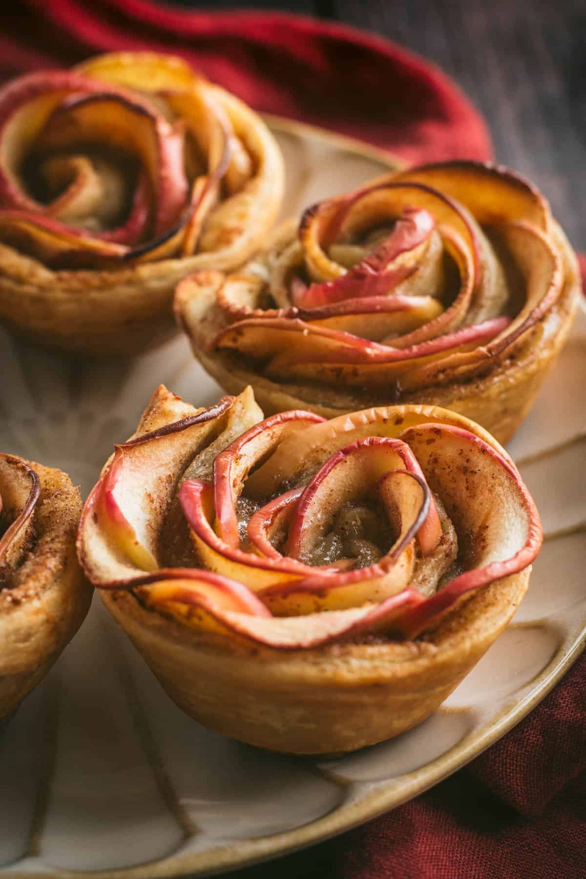 Puff pastry cups filled with sliced apples on a plate.