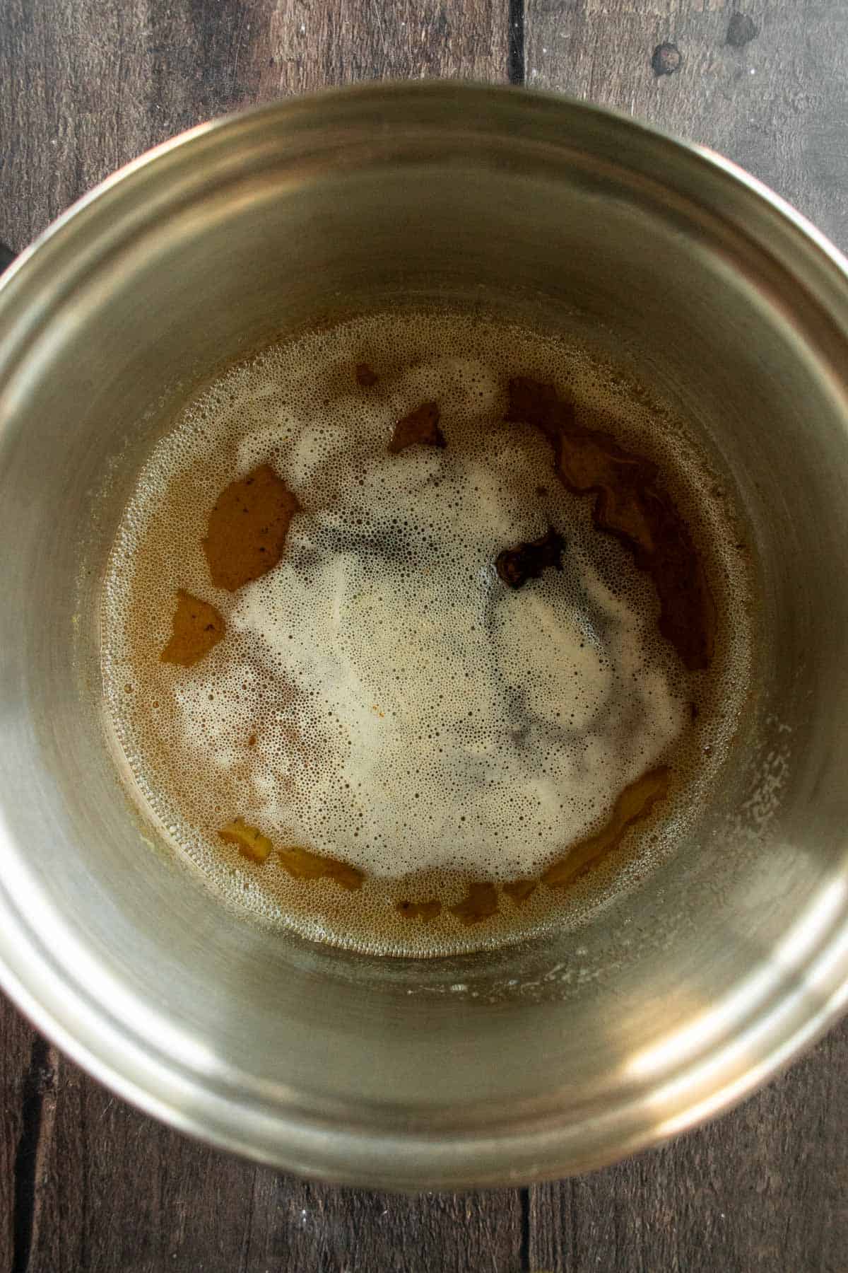 Frothy brown butter in a metal saucepan.