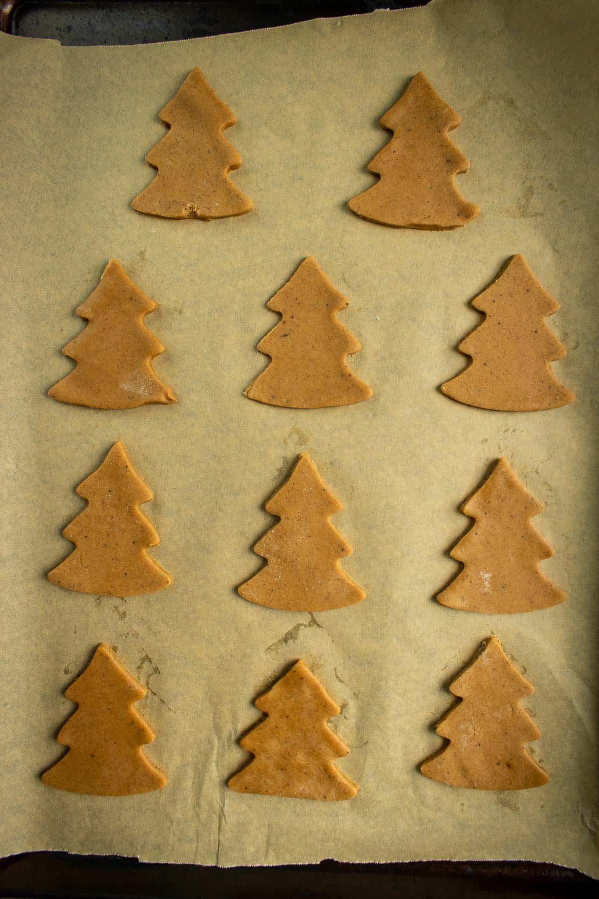 Unbaked tree-shaped cookies arranged on a baking sheet.