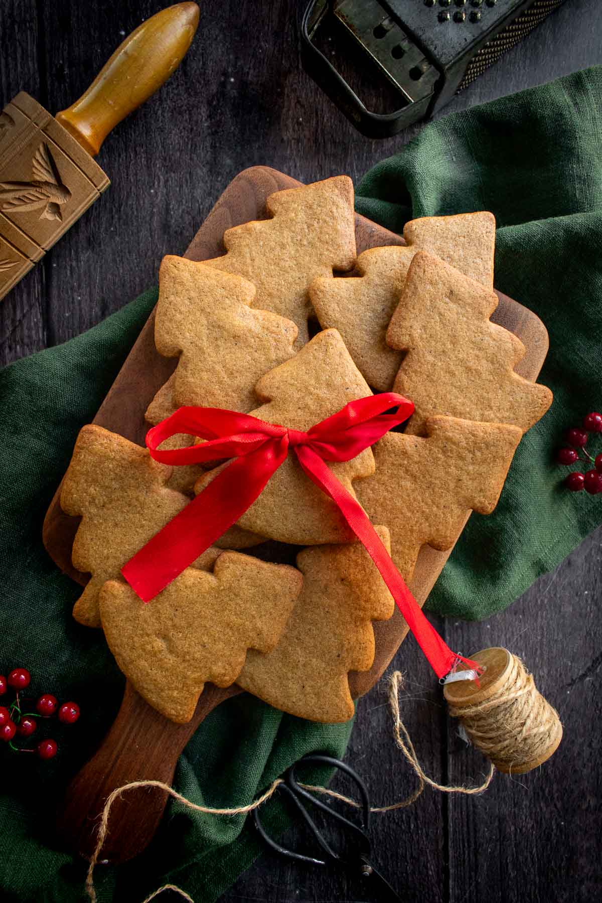 A pile of tree-shaped brown butter cookies on a wood board.