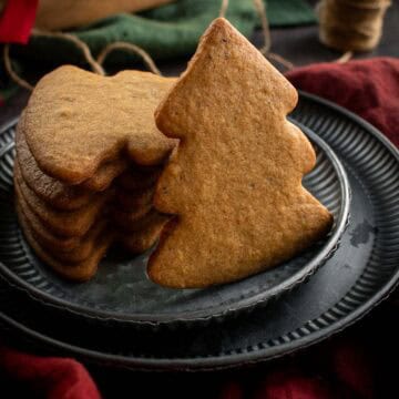 Tree-shaped brown cookies stacked on a metal plate.